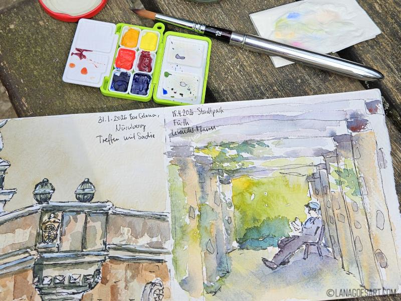 Open sketchbook on a bench with a tiny watercolour palettenext to it, open and filled with Daniel Smith watercolours, a travel brush and a dirty tissue, that was clearly used in the painting process.